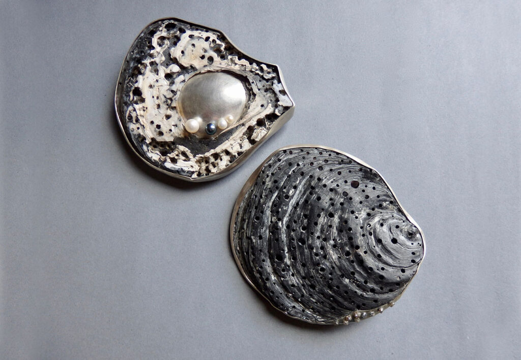 2 Silberbroschen/Anhänger aus einer aufgeschnittenen Muschelschale, mal mit Perlen, mal mit Rohdiamanten